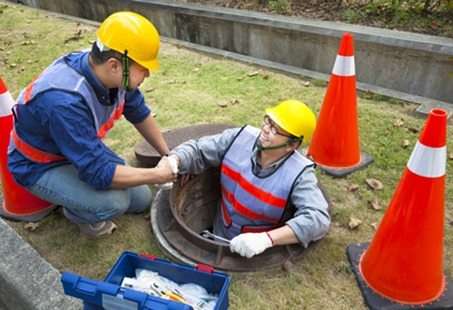 two sewerage workers in the manhole